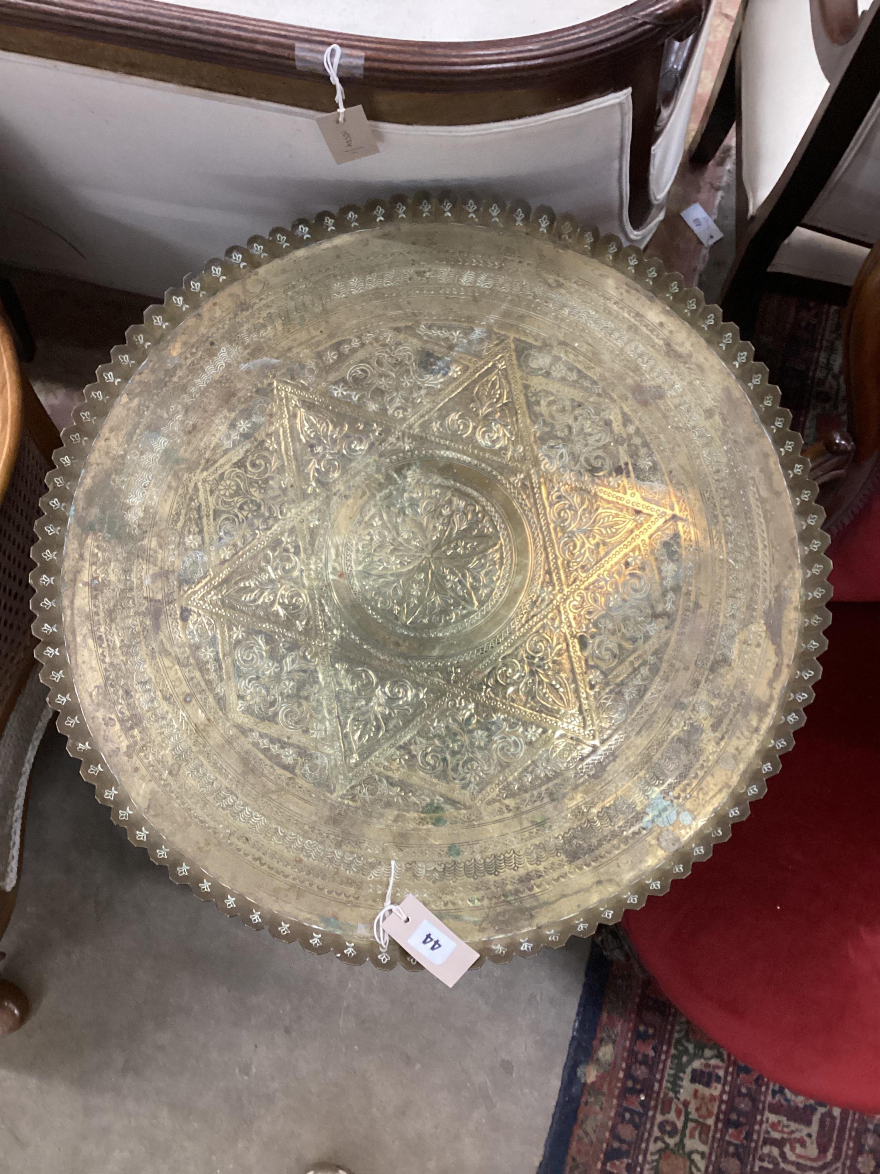 An early 20th century circular engraved brass tray top table on folding bamboo stand, diameter 64cm, height 72cm. Condition - fair